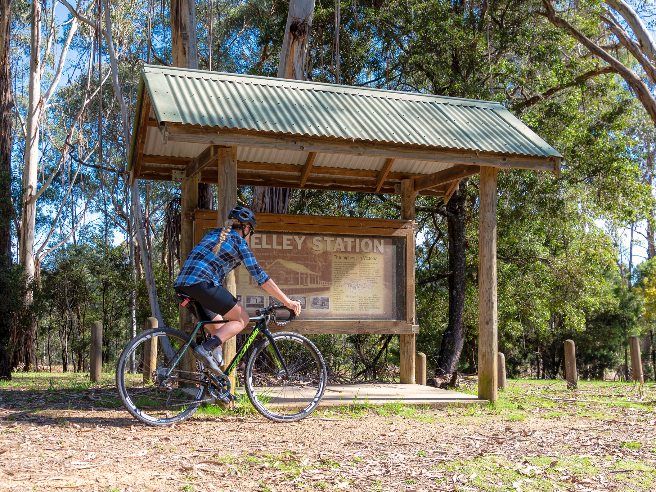 A cyclist at the old Shelley Station sign on the High Country Rail Trail